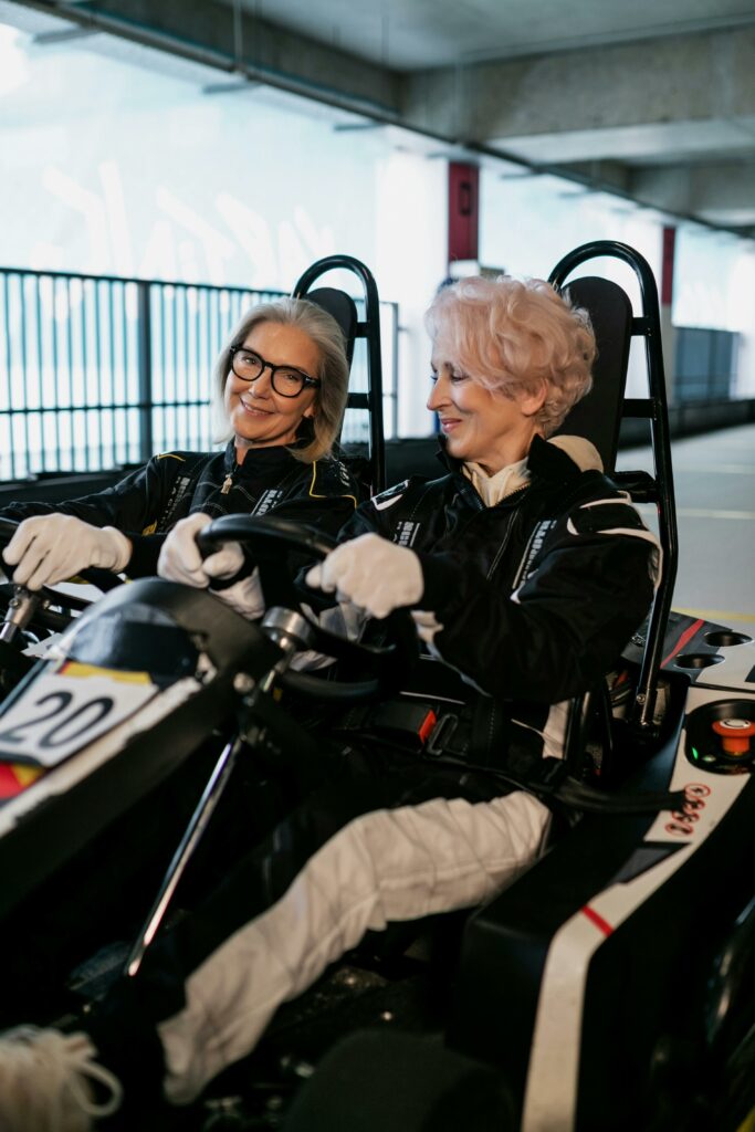 Two senior women enjoying an exciting indoor go-karting experience together.