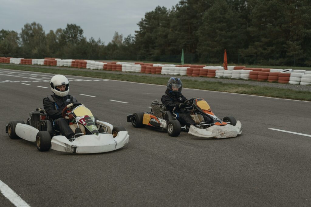 Two athletes competing in a high-speed go-karting race on an outdoor track.